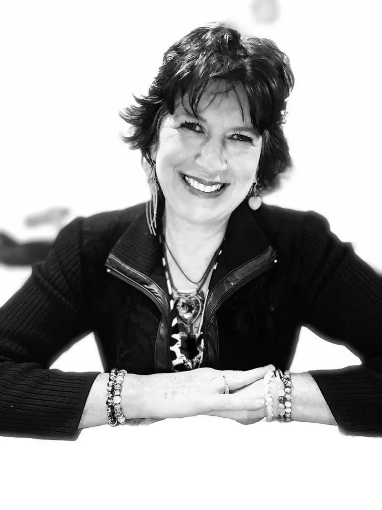 A woman with her arms crossed sitting at the table.