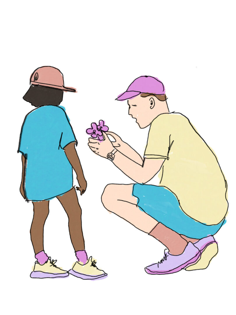 A man kneeling down next to a boy holding flowers.