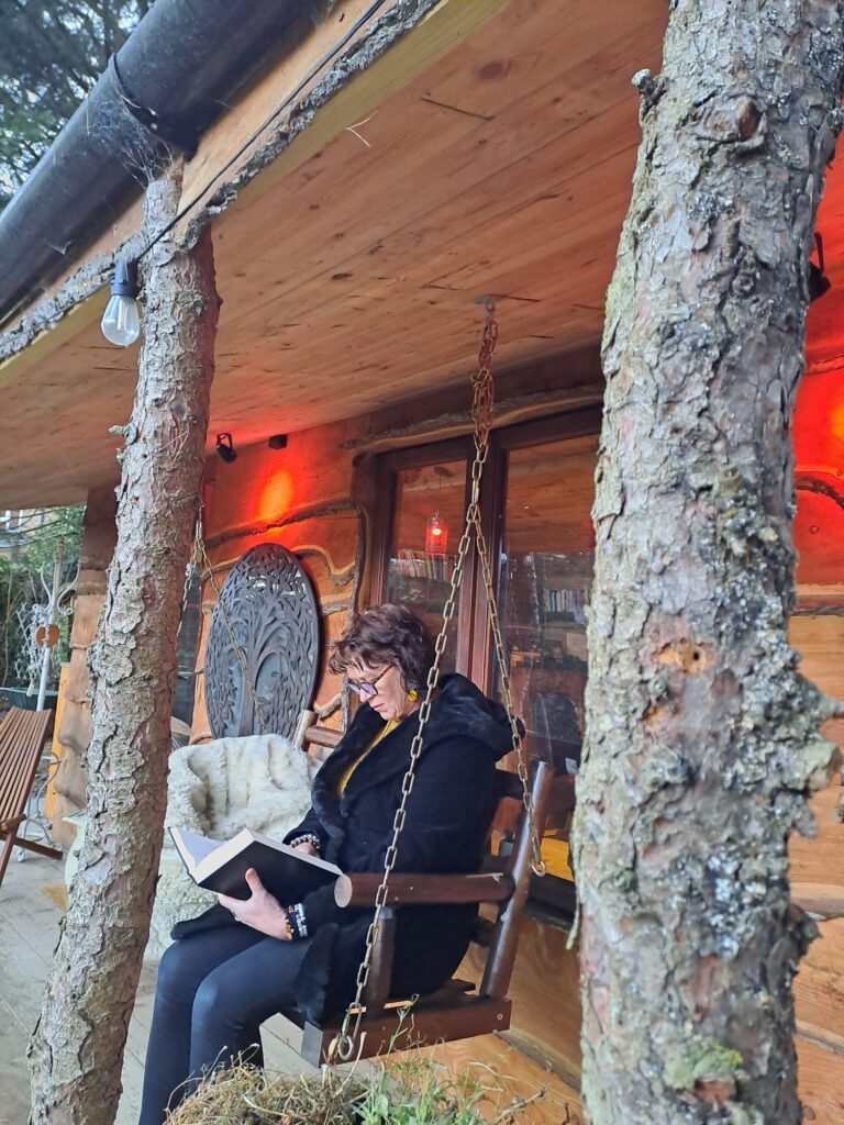 Two people sitting on a bench outside of a cabin.