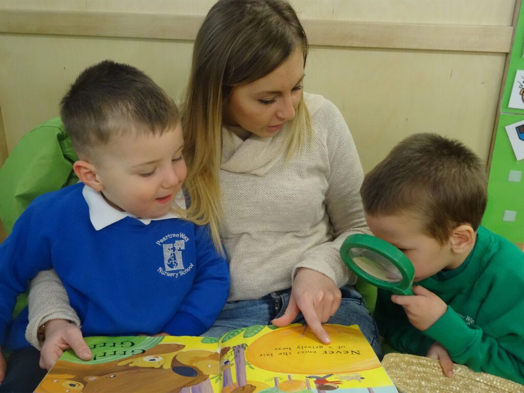 A woman and two children looking at something on the table.