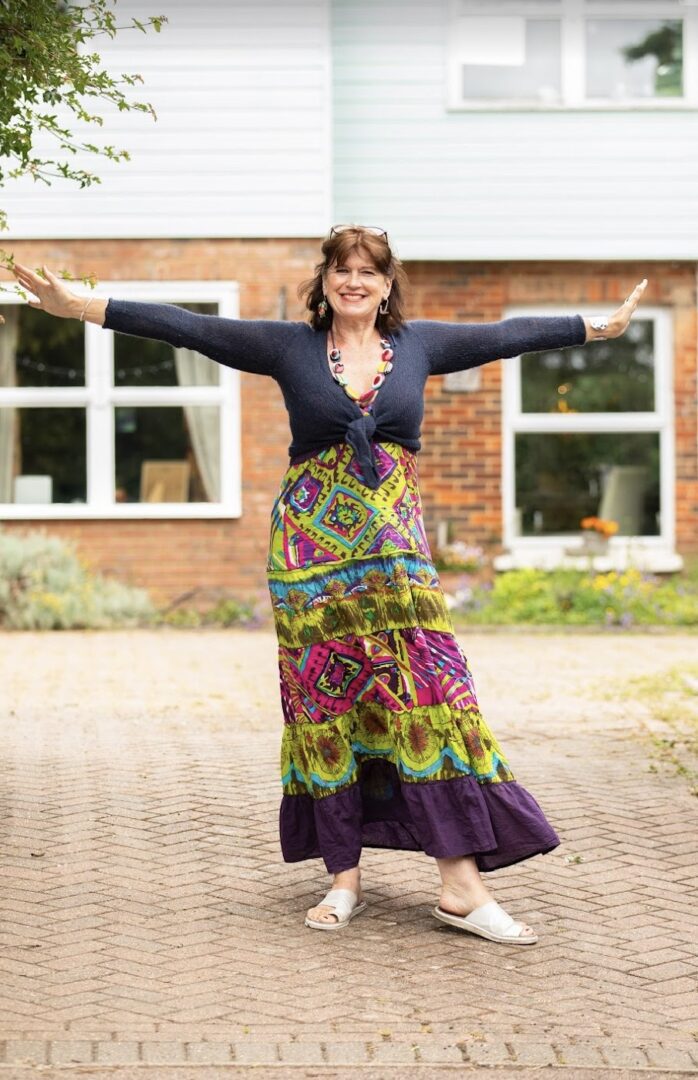 A woman standing on the sidewalk with her arms outstretched.