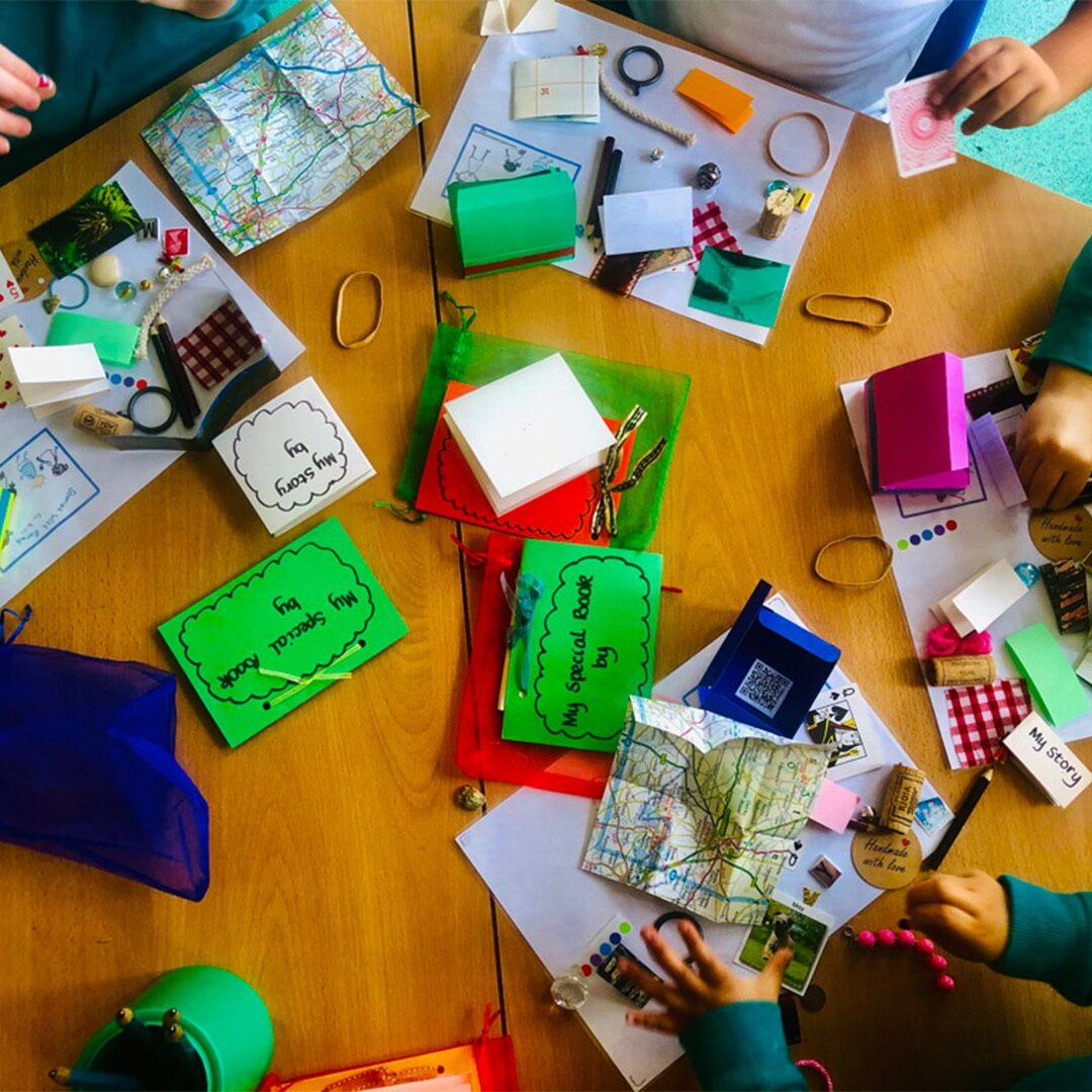 A group of people sitting around a table with many items.